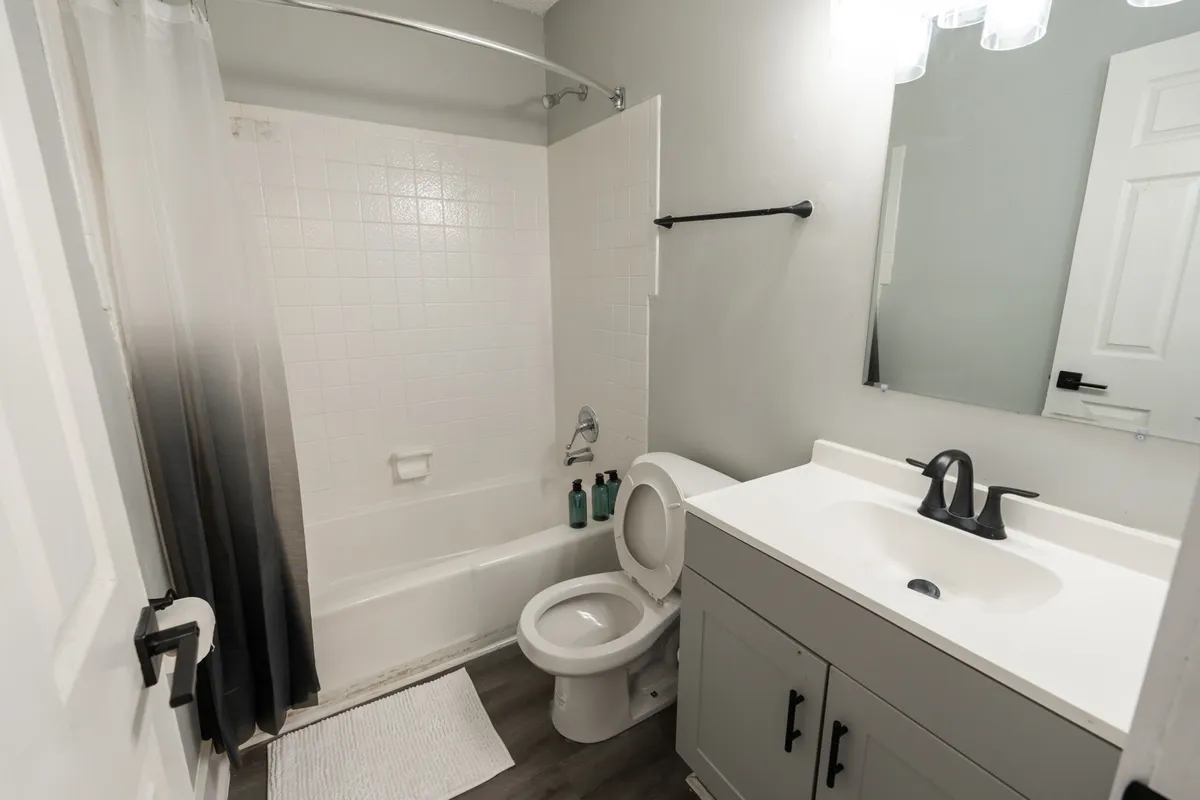 A modern, well-appointed bathroom featuring a sleek vanity with sink, a bathtub for relaxation, a toilet, and a large mirror. The room feels calm, clean, and perfectly suited for unwinding after a busy day.
